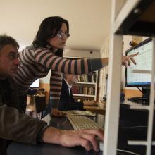 A librarian points out information on a computer screen to a farmer.