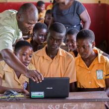 Teacher George Ebo Brown showing children at Archbishop Amissah Junior High School in Western Region how to use a laptop computer. Photo by Ryan Yingling.