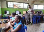 Women and youth learning to use computers, being instructed by a librarian, in a library.