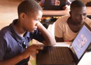 Young women learning to use laptop computer in a library.