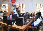 Librarian training people to use desktop computers in Mbarara Public Liibrary.