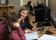 Two young girl students working at their desks in a university library.