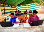 Women and youth learning ICT skills in a tented enclosure at Nyarushanje Community Library.