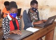 Two young women learning computer skills in a Ugandan public library.