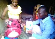 Zariakah Kyozira practising new baking skills at home, watched by Isa Maganda, Isa Maganda, Chief Librarian at Nambi Sseppuuya Community Resource Centre in Uganda.