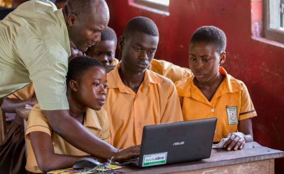 teacher showing children a laptop computer