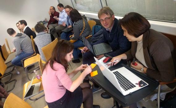 Participants in the open science trainer bootcamp in Debrecen, Hungary, get to grips with open science training methods. Photo by Gwen Franck (CC BY). People sitting and working in groups open science trainer bootcamp in Debrecen, Hungary.