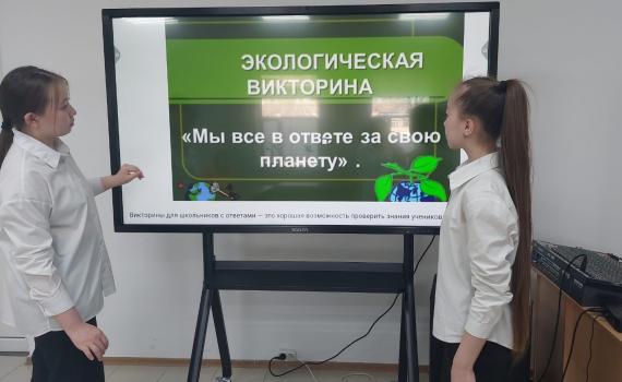 Two young girls with a screen showing information about the eco-centre.