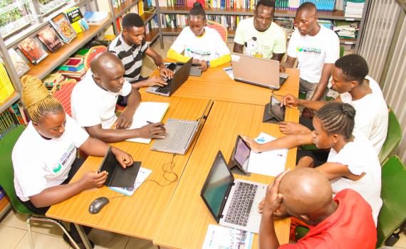 A group of young adults learning online safety skills, using laptops, in Fahari Community Library. 