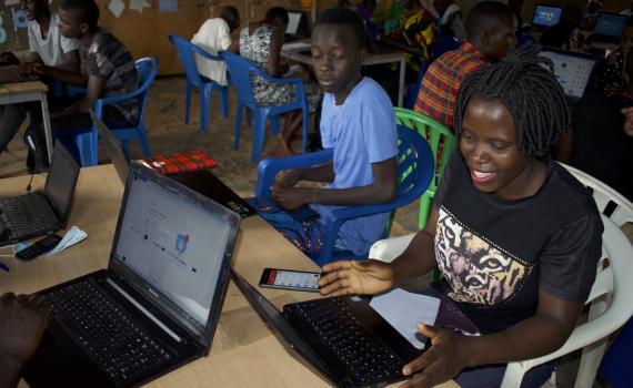 Women and young people learning how to use ICT, with laptops.