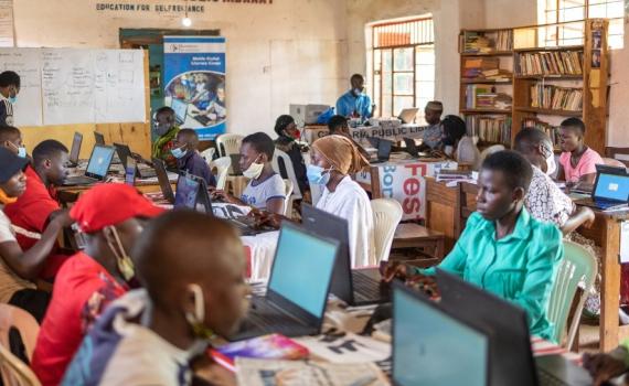 Young people and women learning ICT skills in a library in Uganda.