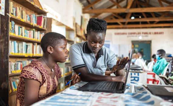 A teacher showing a young women how to use a computer in Caezxaria Public Library in Uganda. 