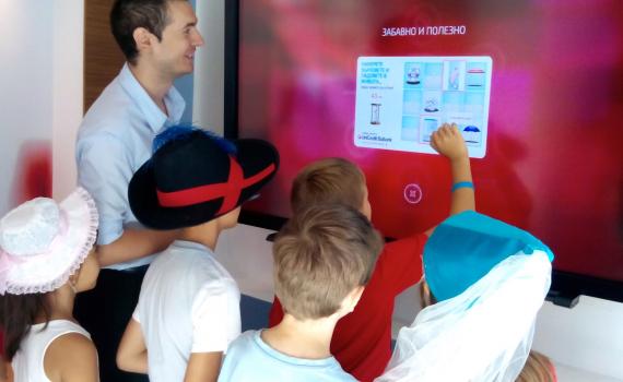 Children in the bank using touchscreen to learn about bank services