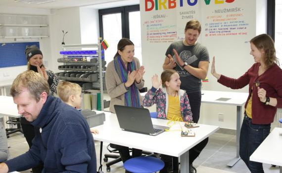 librarians, parents and children with a computer in the maker space
