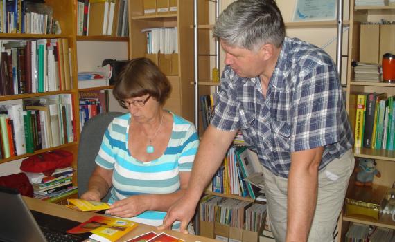 A librarian shows a farmer how to produce brochures.