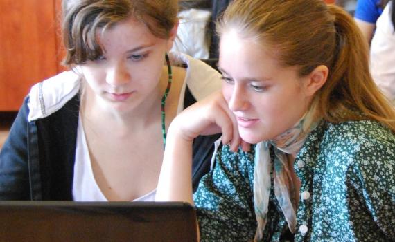 Two teenaged girls researching the internet on a desktop computer.