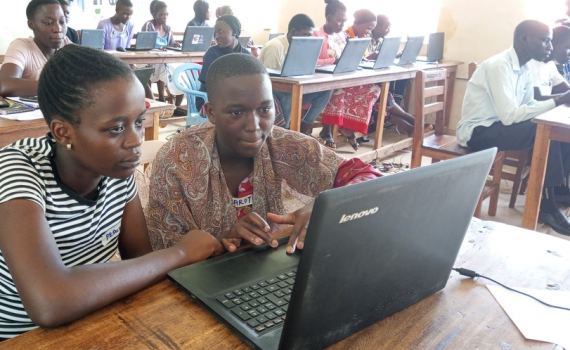 Women and youth in the library, with computers, learning ICT skills.