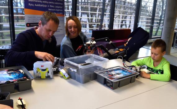 Parents and a child learning robotics skills in the library.